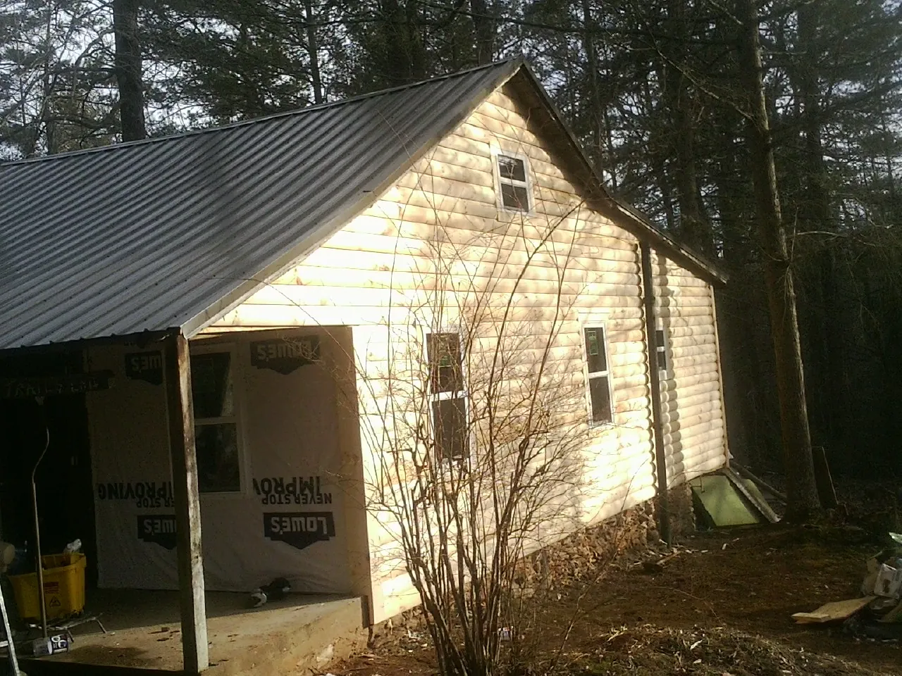 Log siding gable end under a dark metal roof edge in Cardwell