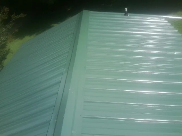 New green metal panels meeting at the ridge of a roof — Flat Roof Repair work by our crew in Cardwell