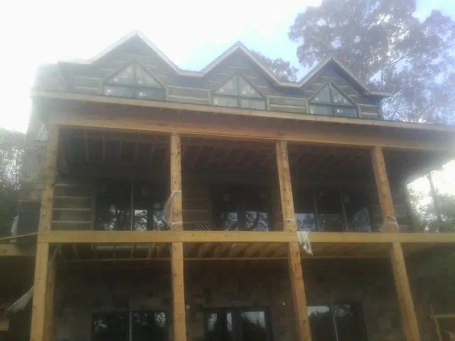 Dormers and porch framing on a large log home under construction — Roof Coating work by our crew in Cardwell