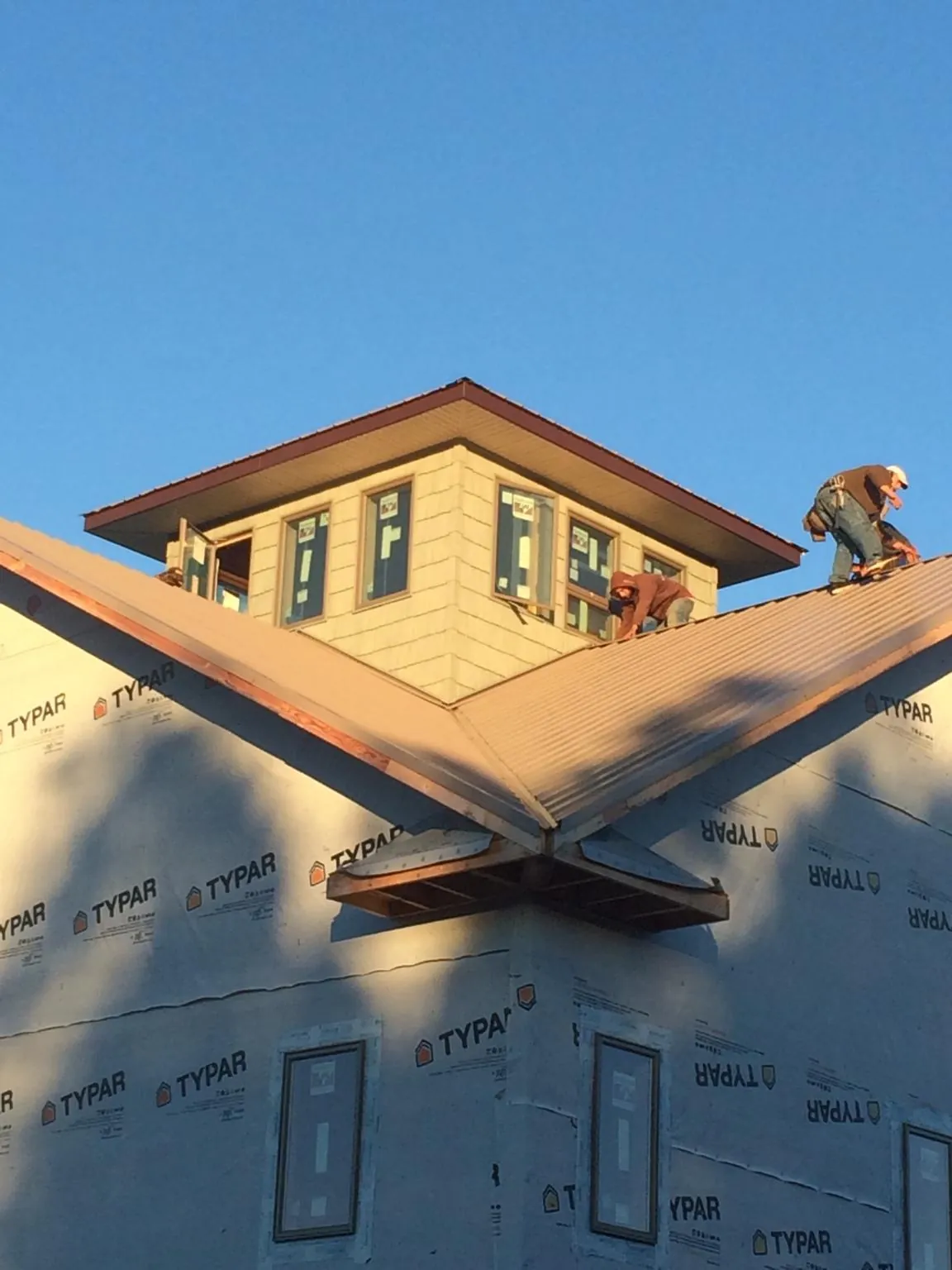 Roofers working around a rooftop cupola on a new metal roof at sunset — Roof Waterproofing in Cardwell by Roofing Brothers